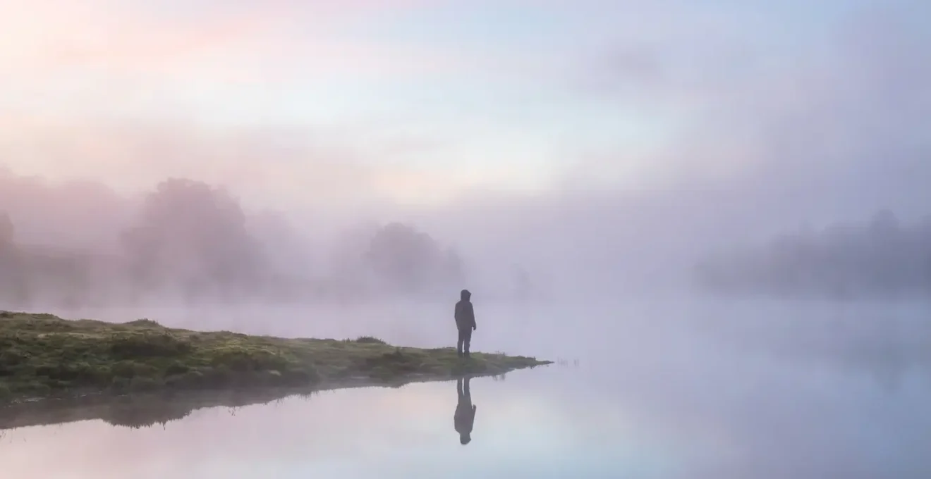 Figura sfocata riflessa in specchio d'acqua con nebbia eterea