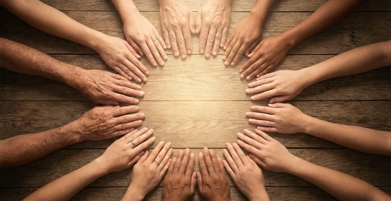 Cerchio di mani diverse unite viste dall'alto con luce calda al centro