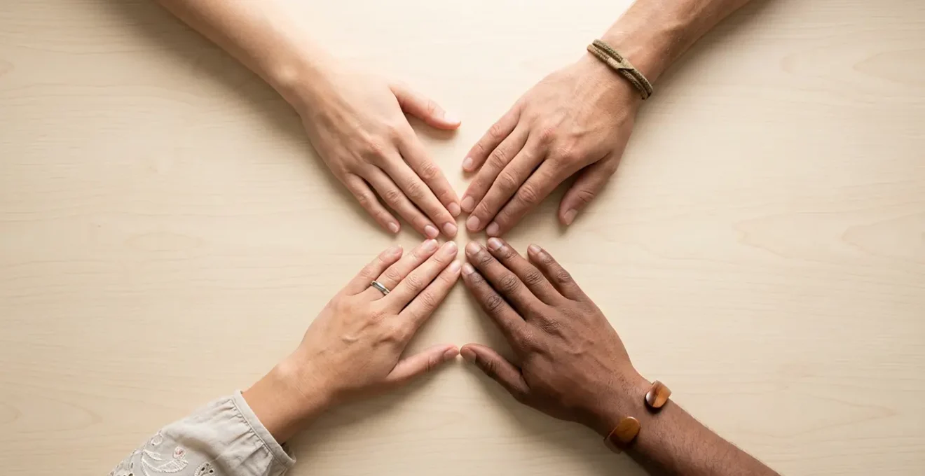 Vista dall'alto di quattro mani diverse che si uniscono al centro formando un cerchio